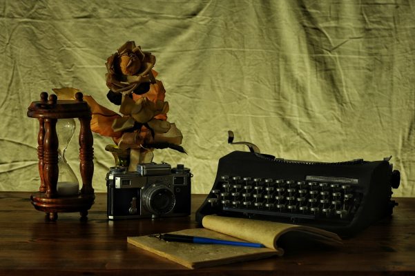 Canva - Brown Notebook in Between of a Type Writer and Gray and Black Camera
