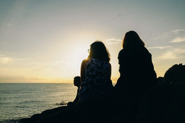 Canva - Silhouette of Two Women Facing Body of Water